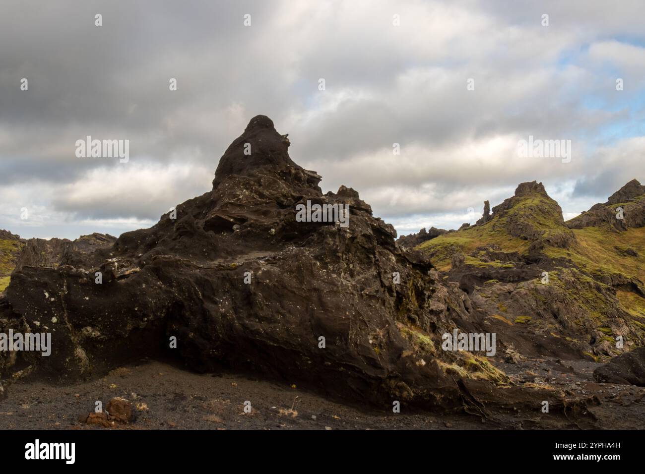 Particolare di rocce vulcaniche di varie forme, parzialmente ricoperte da muschio e licheni. Cielo blu con nuvole bianche. Katla geopark, Islanda. Foto Stock