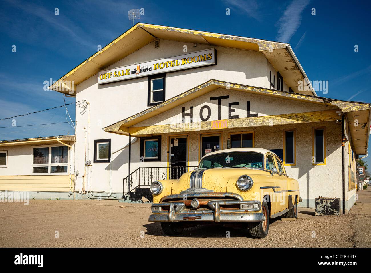 Un'auto gialla è parcheggiata di fronte a un hotel. L'hotel e' vecchio e presenta uno schema colore giallo e bianco Foto Stock