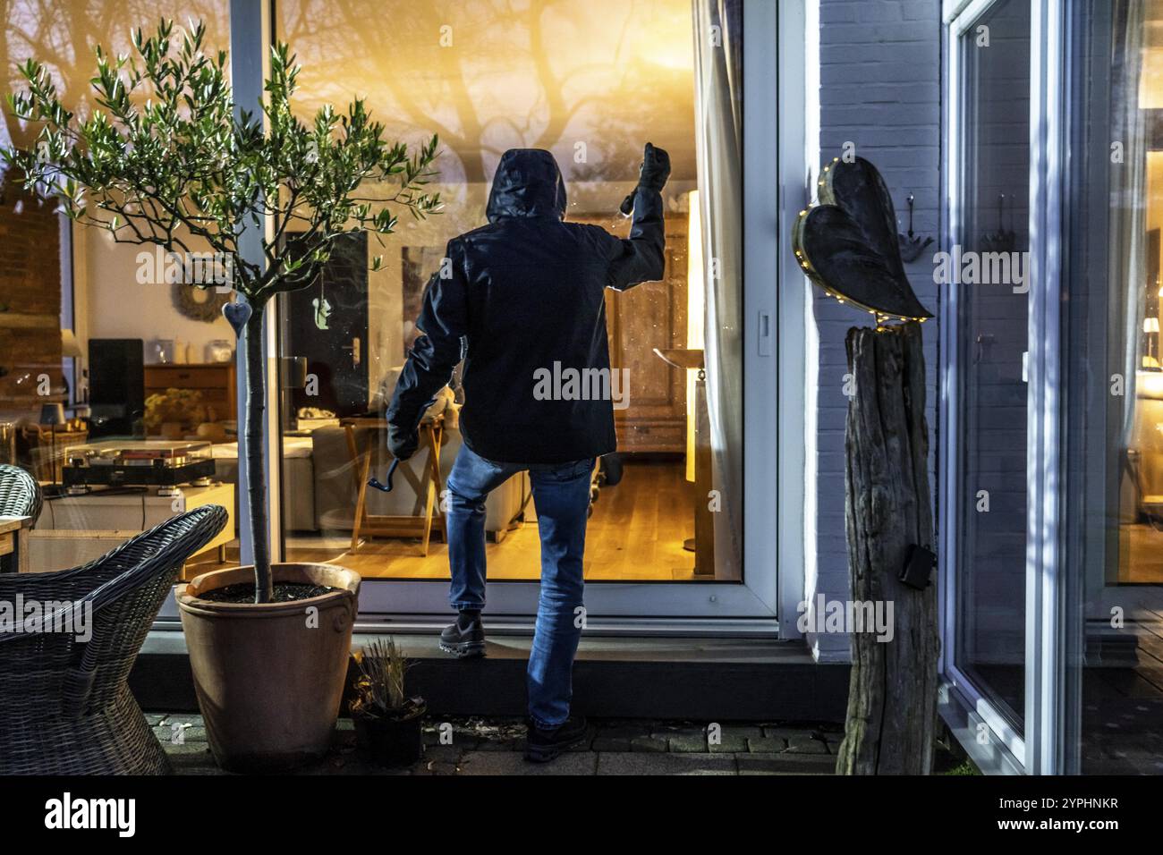 Immagine simbolica di un ladro, l'esecutore spia su un appartamento dal lato del giardino Foto Stock