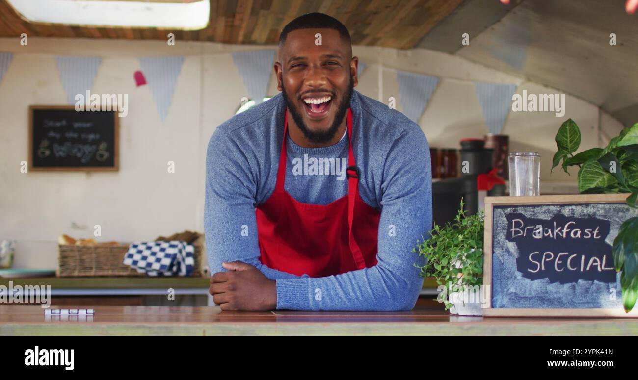 Ritratto di un uomo afroamericano che indossa il grembiule sorridente mentre si trova nel furgone del cibo Foto Stock