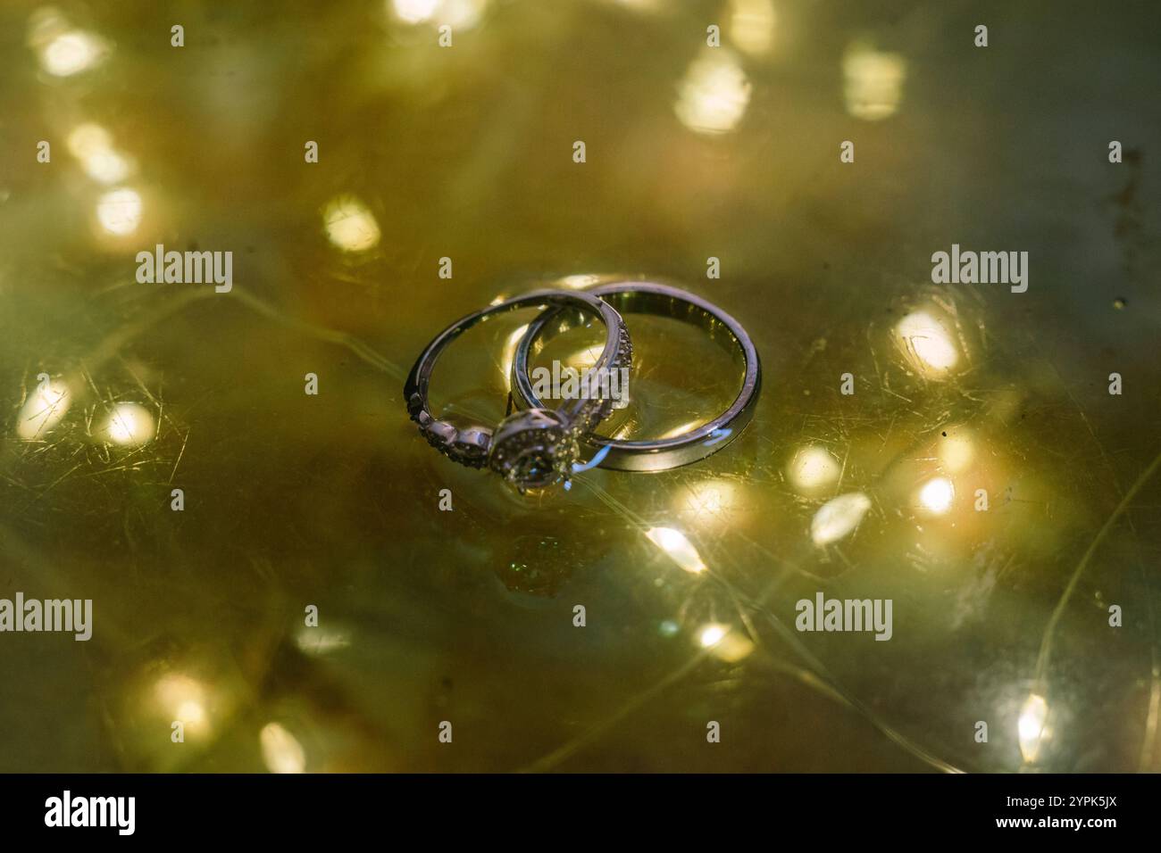 Una fede nuziale posizionata sopra una lampada di vetro che riflette splendidamente la luce, perfetta per catturare momenti romantici ed eleganti Foto Stock