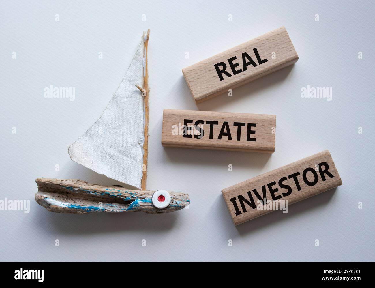 Simbolo dell'investitore immobiliare. Blocchi di legno con parole "investitore immobiliare". Bellissimo sfondo bianco con barca. Business and Real Estate Investor co Foto Stock