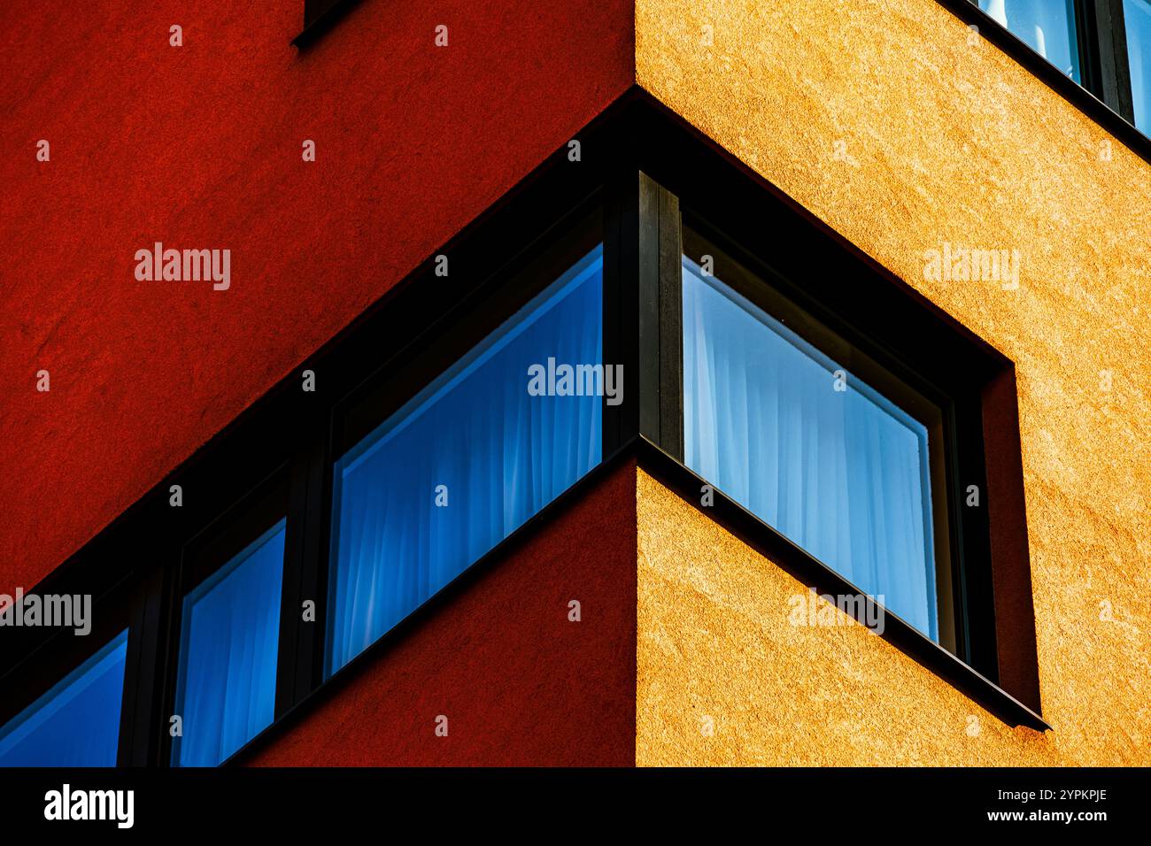 Vivace angolo degli edifici con facciata rossa e gialla a contrasto e finestre riflettenti Foto Stock