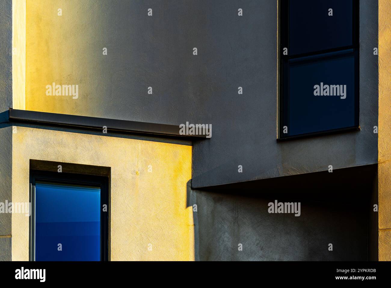 Composizione architettonica minimalista con ombre audaci, luce calda e riflessi delle finestre a contrasto Foto Stock