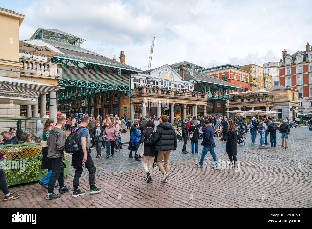 Affollata folla di turisti e gente del posto al Covent Garden Market di Londra, con la sua caratteristica architettura vittoriana e le opere di ferro verdi in una giornata nuvolosa Foto Stock