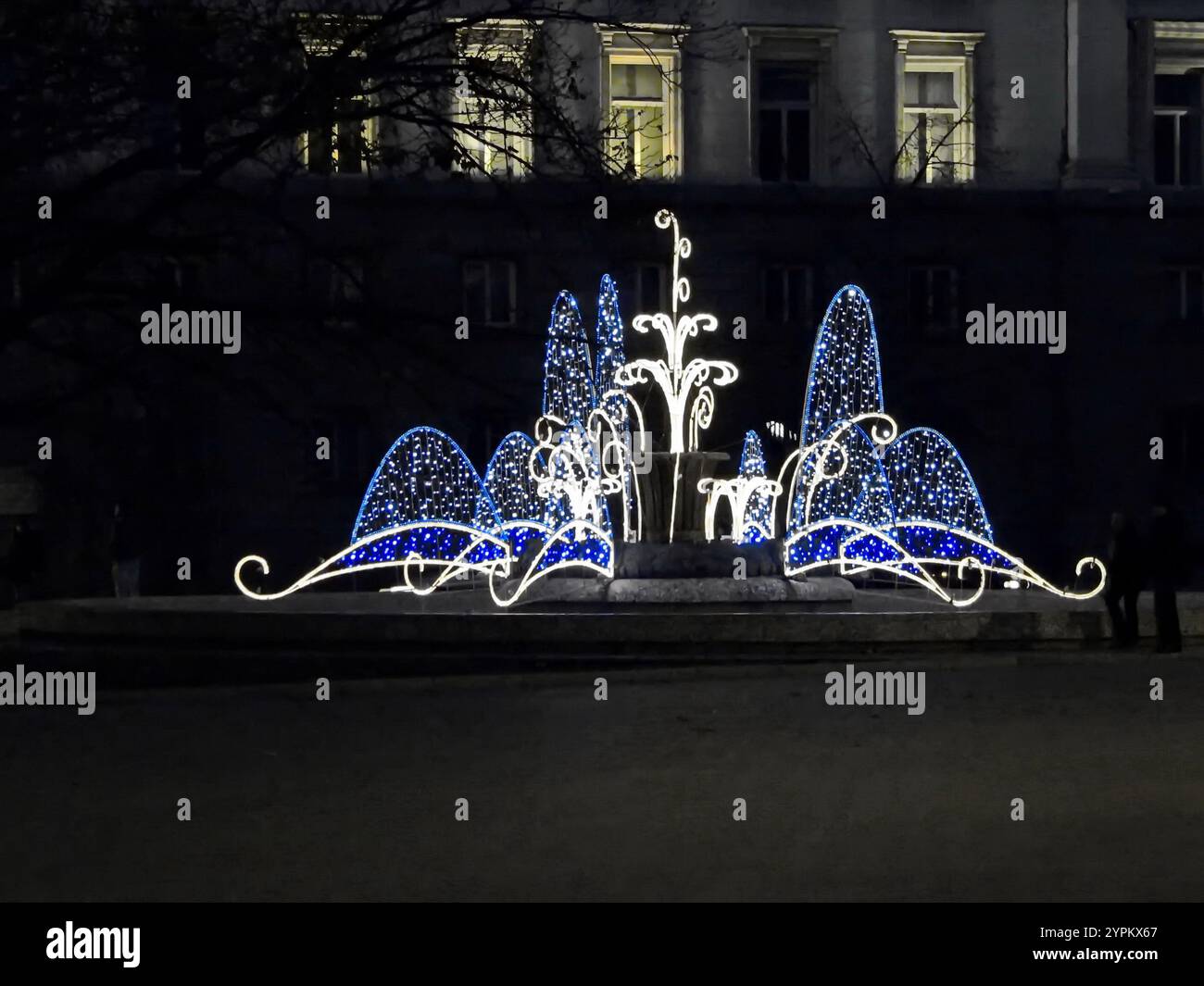 Vista serale di una splendida combinazione luminosa di bianco e blu da diversi impianti di illuminazione su una vecchia fontana prima di Capodanno, Sofia, Bulgaria Foto Stock