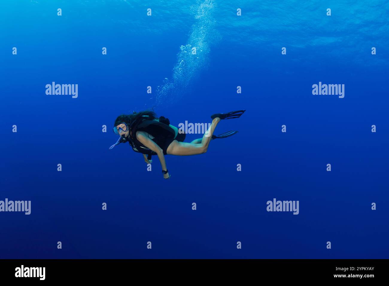 Un tuffatore solitario (MR) nuota in acque blu dell'oceano aperto al largo dell'isola di Yap, Micronesia. Foto Stock