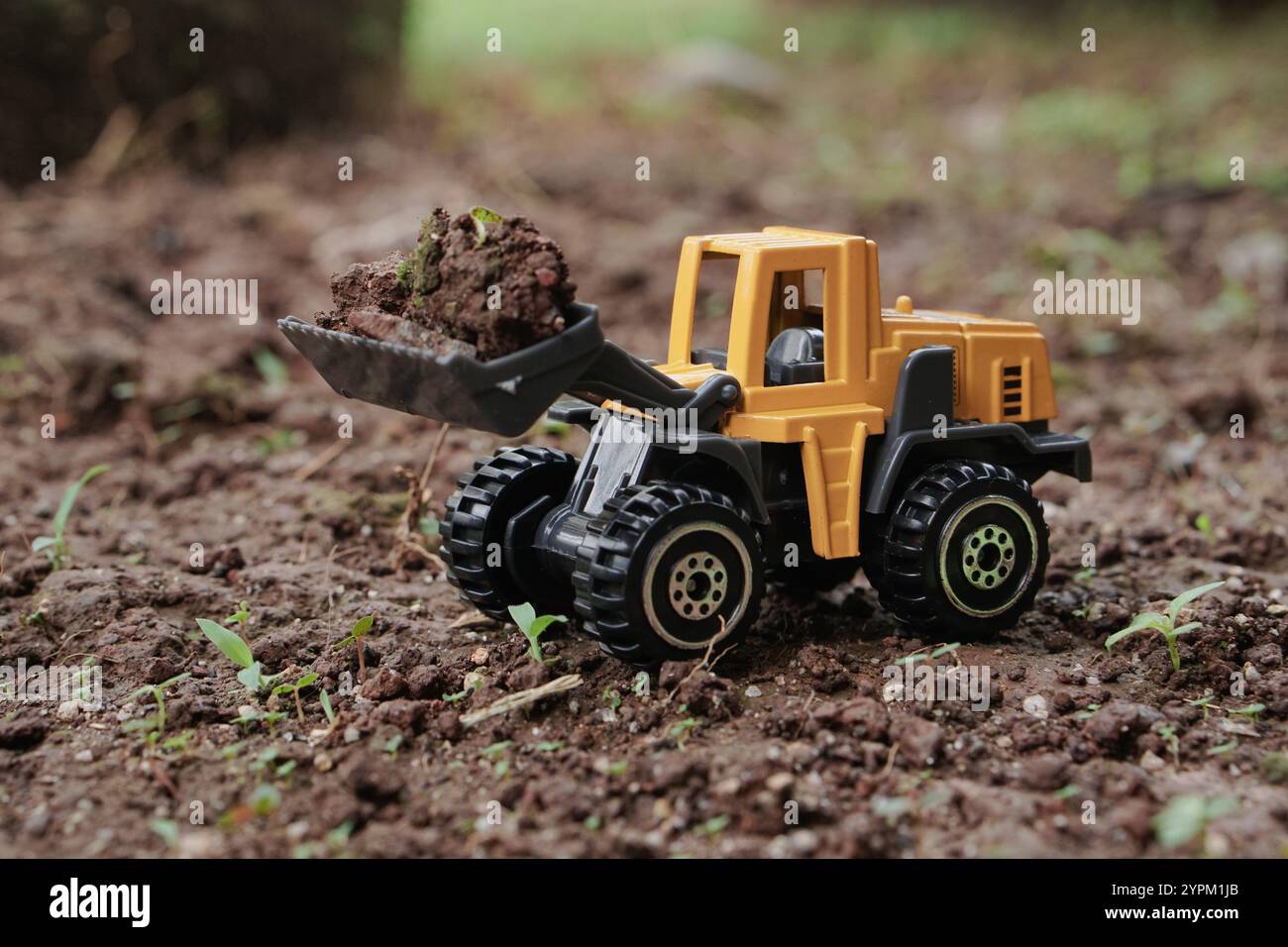 Angolo di visione laterale dello sfondo esterno esterno del terreno di sollevamento del trattore o della pala gommata gialla. concetto dell'immagine di costruzione con attrezzature pesanti. Foto Stock