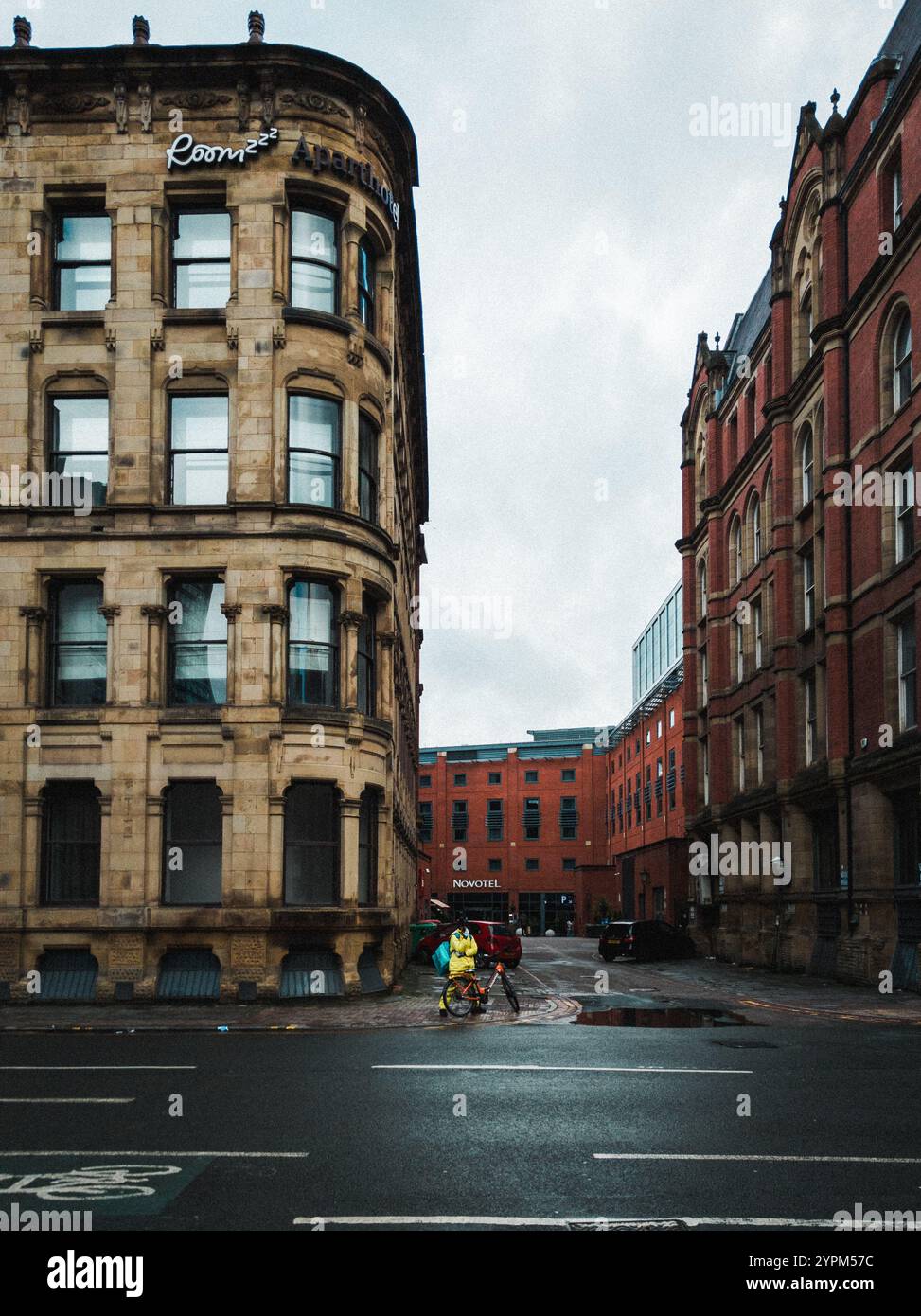 Urban Street Scene con architettura storica e ciclista in Rain Gear Foto Stock