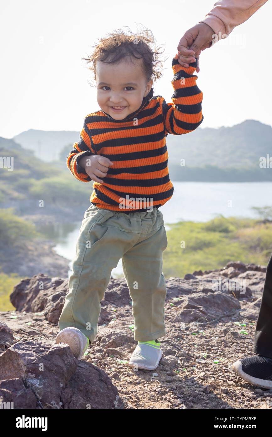 Figlio che tiene in mano le dita della madre sulla cima della montagna con vista sul lago Foto Stock