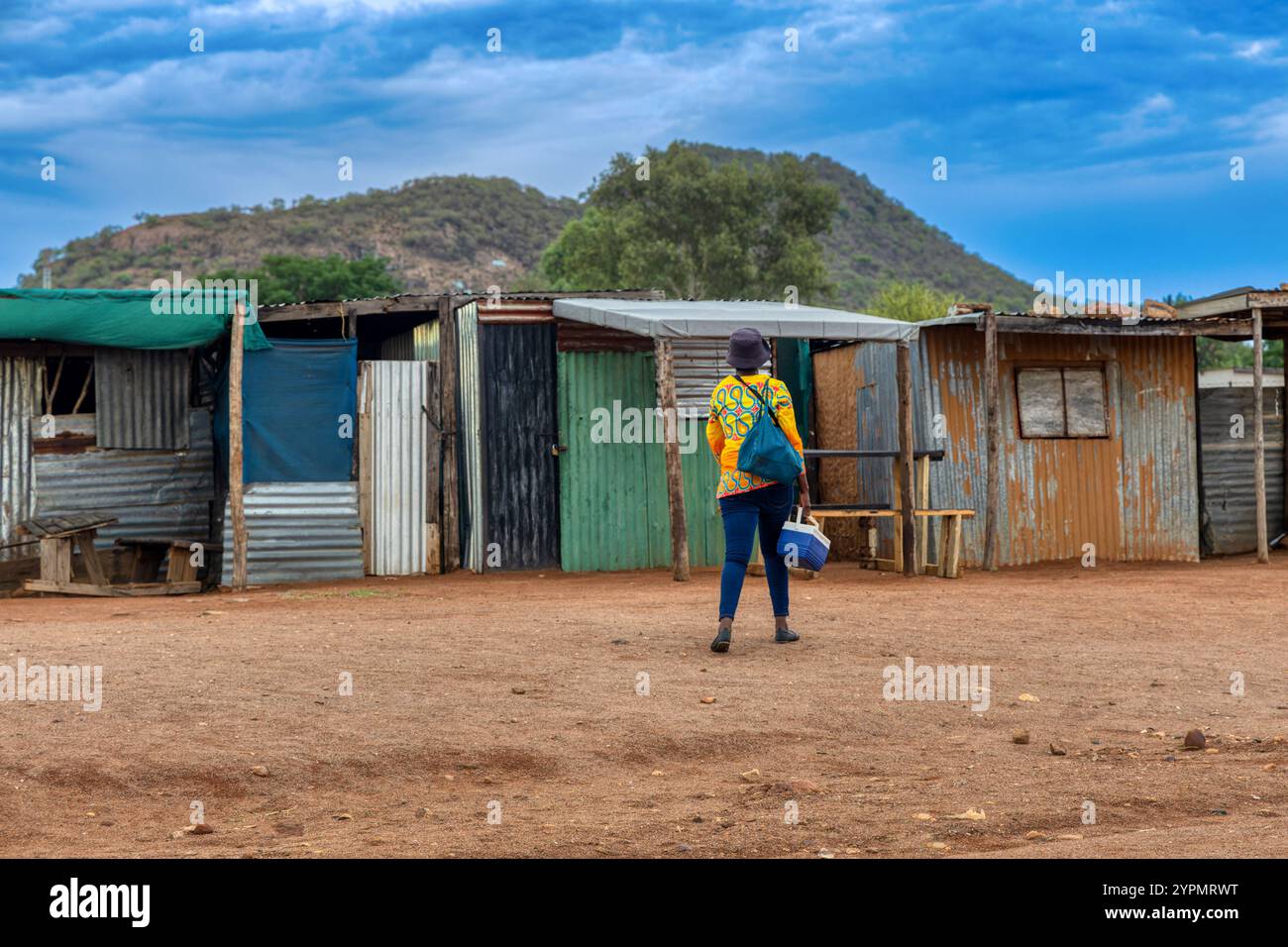 lavoratrice africana che va a lavorare la mattina nella baraccopoli, sud africa, baracca in lamiera ondulata zincata Foto Stock