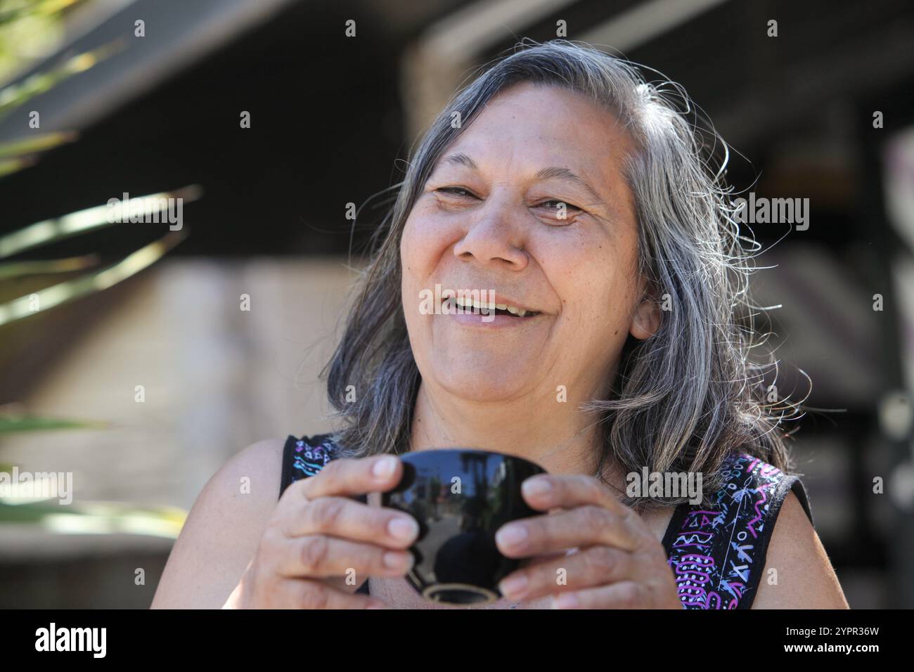 donna latina anziana che beve caffè o tè all'aperto nelle soleggiate giornate estive Foto Stock