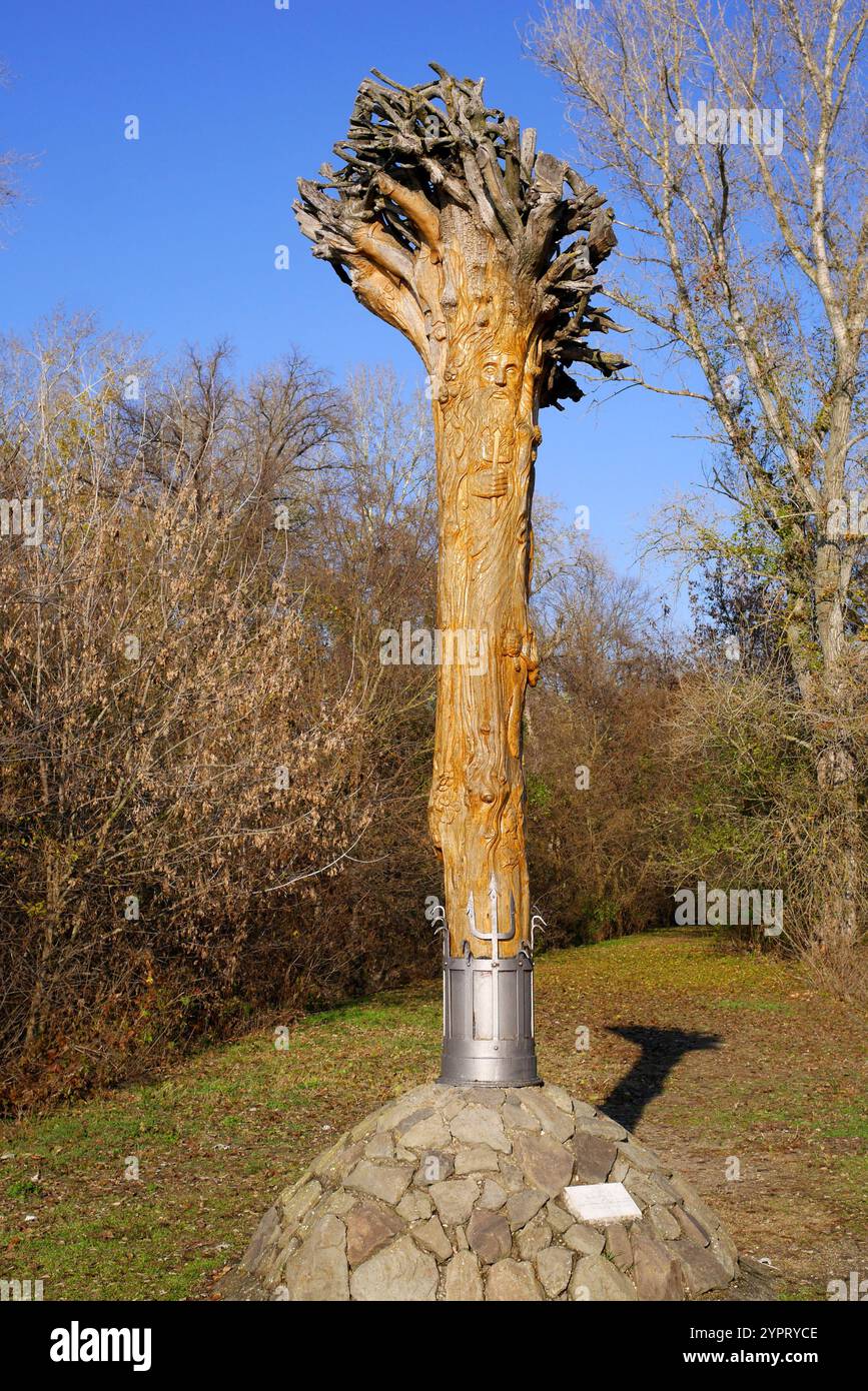 Pilastro del tronco d'albero in legno scolpito alla confluenza del ramo principale del Danubio e del ramo sussidiario Soroksar, isola di Csepel, Ungheria. Foto Stock