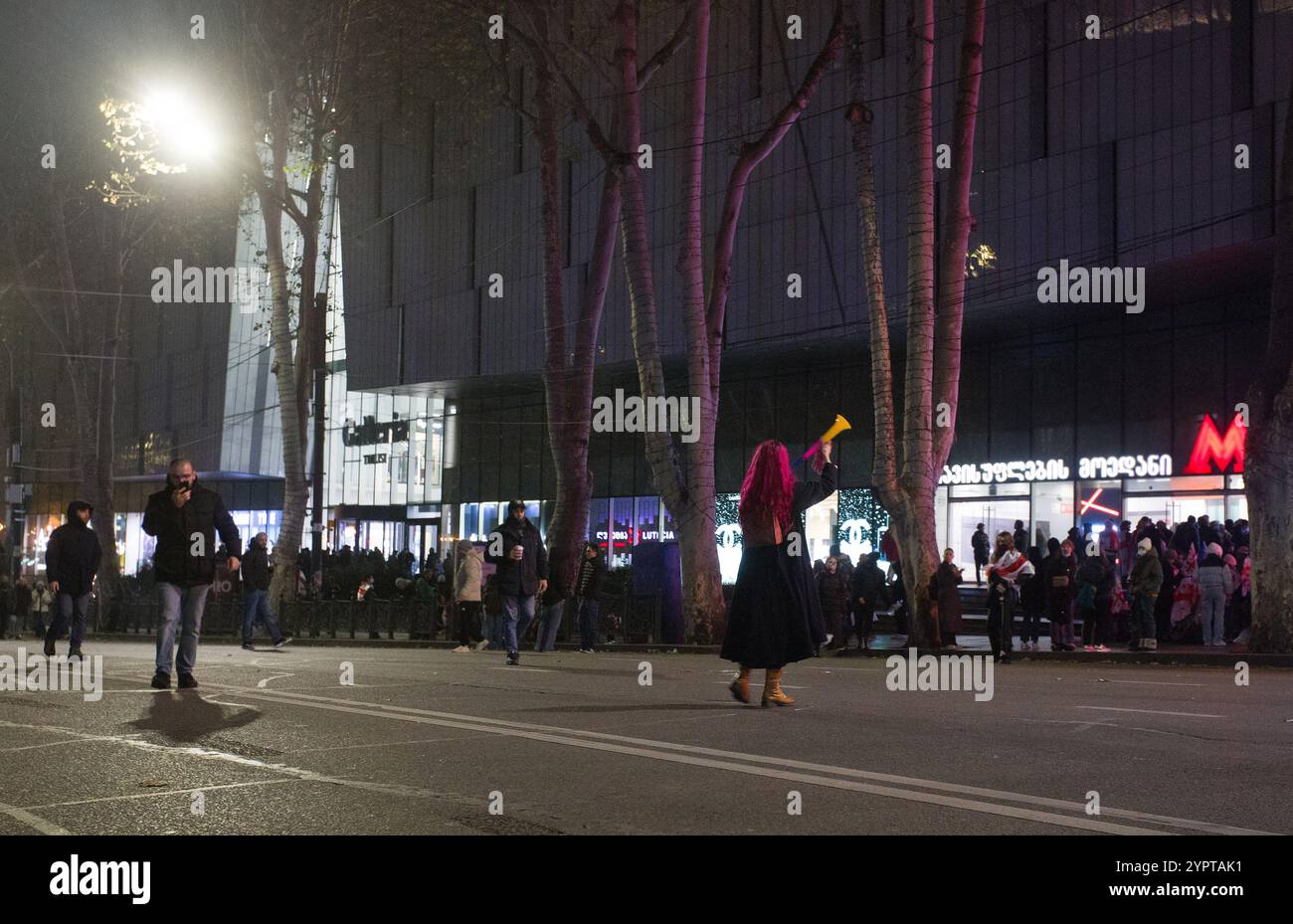 12-1-2024 tbilisi ge giovane donna con capelli rossi SOFFIA THW VUVUZELA - partecipa alle proteste (manifestazioni pacifiche contro il disonesto Foto Stock