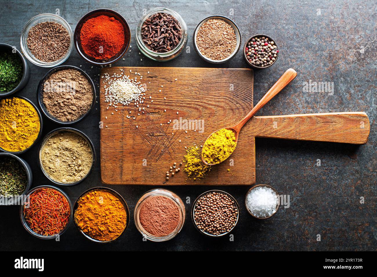 Erbe e spezie colorate per cucinare i pasti. Spezie indiane e asiatiche sullo sfondo del tagliere per uno spazio libero per menu o ricette. Vista dall'alto. Foto Stock