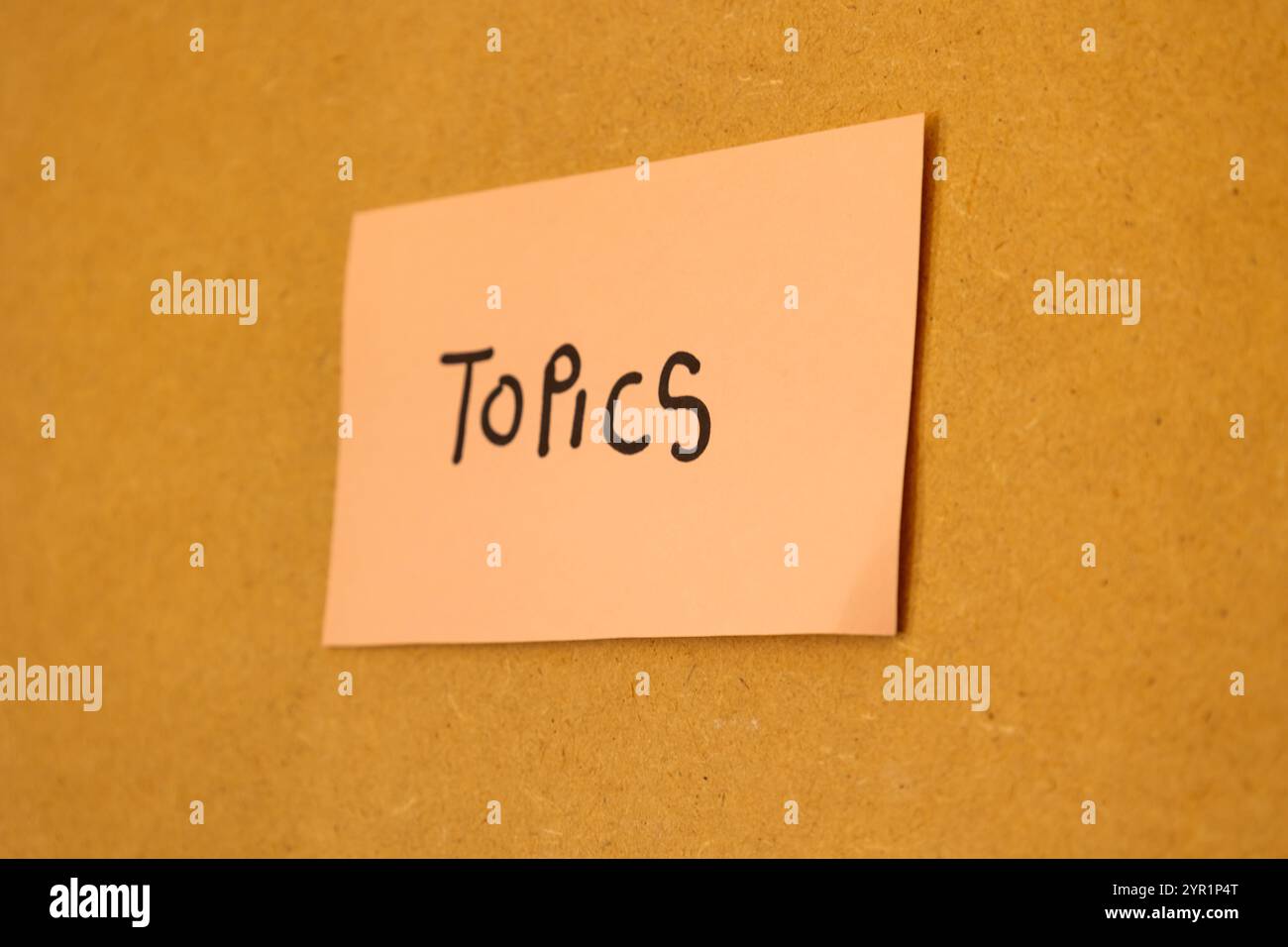 Primo piano di una nota rosa incollata su una lavagna con un messaggio scritto che dice argomenti, concetto di note e argomenti Foto Stock