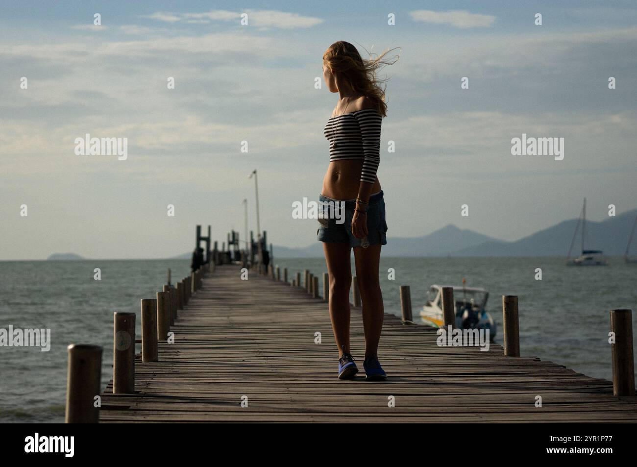 Donna in piedi sul molo sul mare contro il cielo durante il tramonto Foto Stock