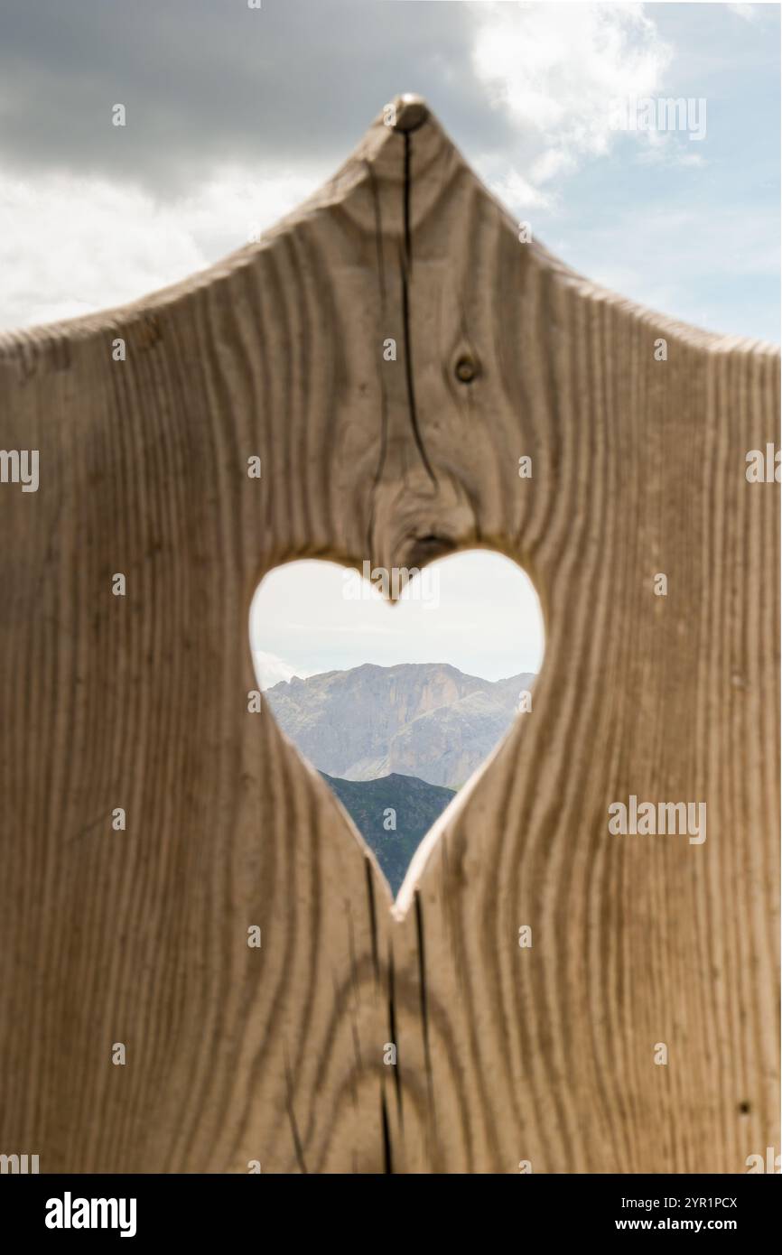 Un cuore intagliato in un pezzo di legno incornicia le montagne nella parte posteriore Foto Stock
