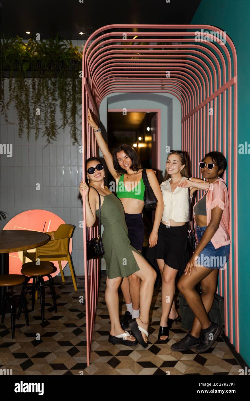 Amiche alla moda in un ambiente informale che si posa insieme al ristorante Foto Stock