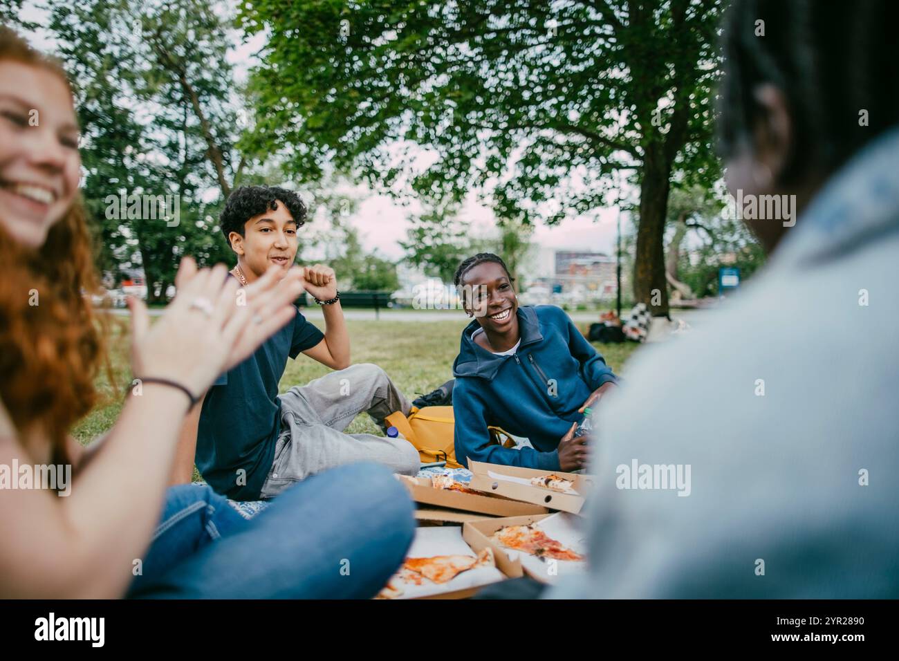 Ragazzi adolescenti felici che si divertono con gli amici seduti nel parco Foto Stock