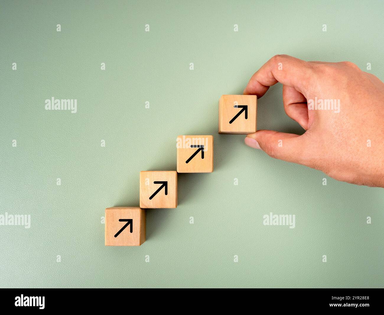 Gestione della crescita degli obiettivi aziendali, nuovo obiettivo, piano di successo, concetti di leadership. Blocchi di cubo di legno disposti a mano da uomo d'affari con l'icona della freccia rivolta verso l'alto Foto Stock