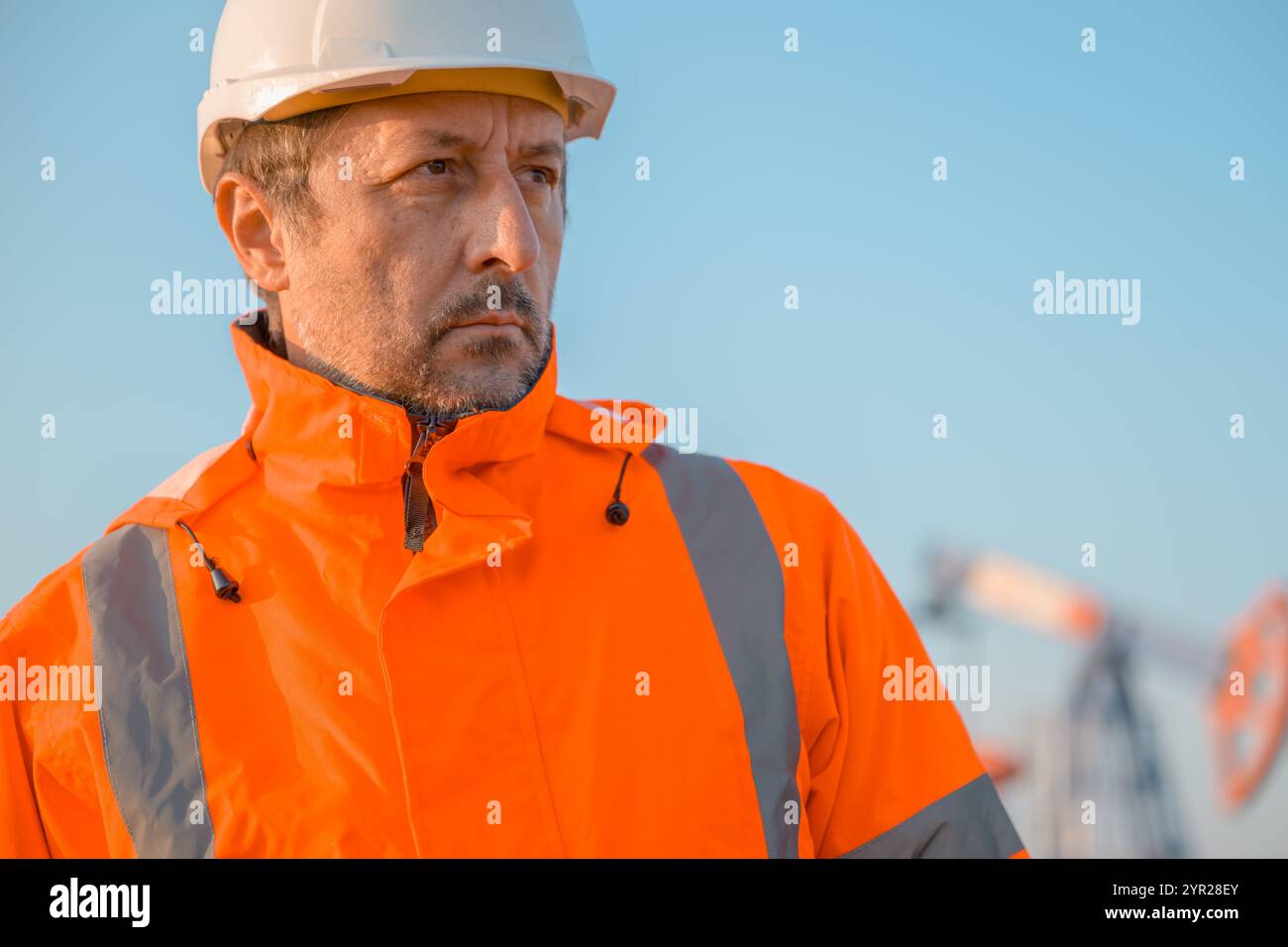 Ingegnere del carro di perforazione che supervisiona il processo di estrazione di petrolio e gas, monitora le prestazioni della pompa dell'olio sul campo, attenzione selettiva Foto Stock