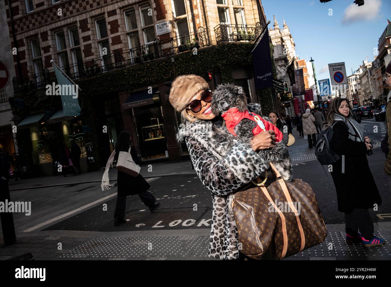 Donna glamour che porta il suo cane da compagnia e la borsa Louis Vuitton a Old Bond Street e Piccadilly, nel cuore del quartiere Mayfair di Londra, in Inghilterra Foto Stock