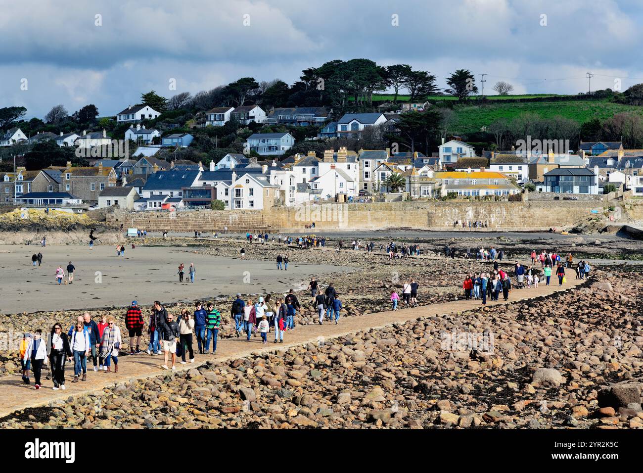 Persone che camminano sulla strada sopraelevata pubblica tra il monte St Michaels e il villaggio di Marazion, con la bassa marea, in Cornovaglia, Inghilterra, Regno Unito Foto Stock