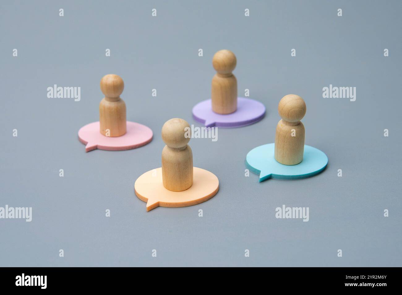Quattro figure di legno, ciascuna in piedi su una bolla di colore diverso, che rappresentano opinioni o prospettive diverse. Foto Stock