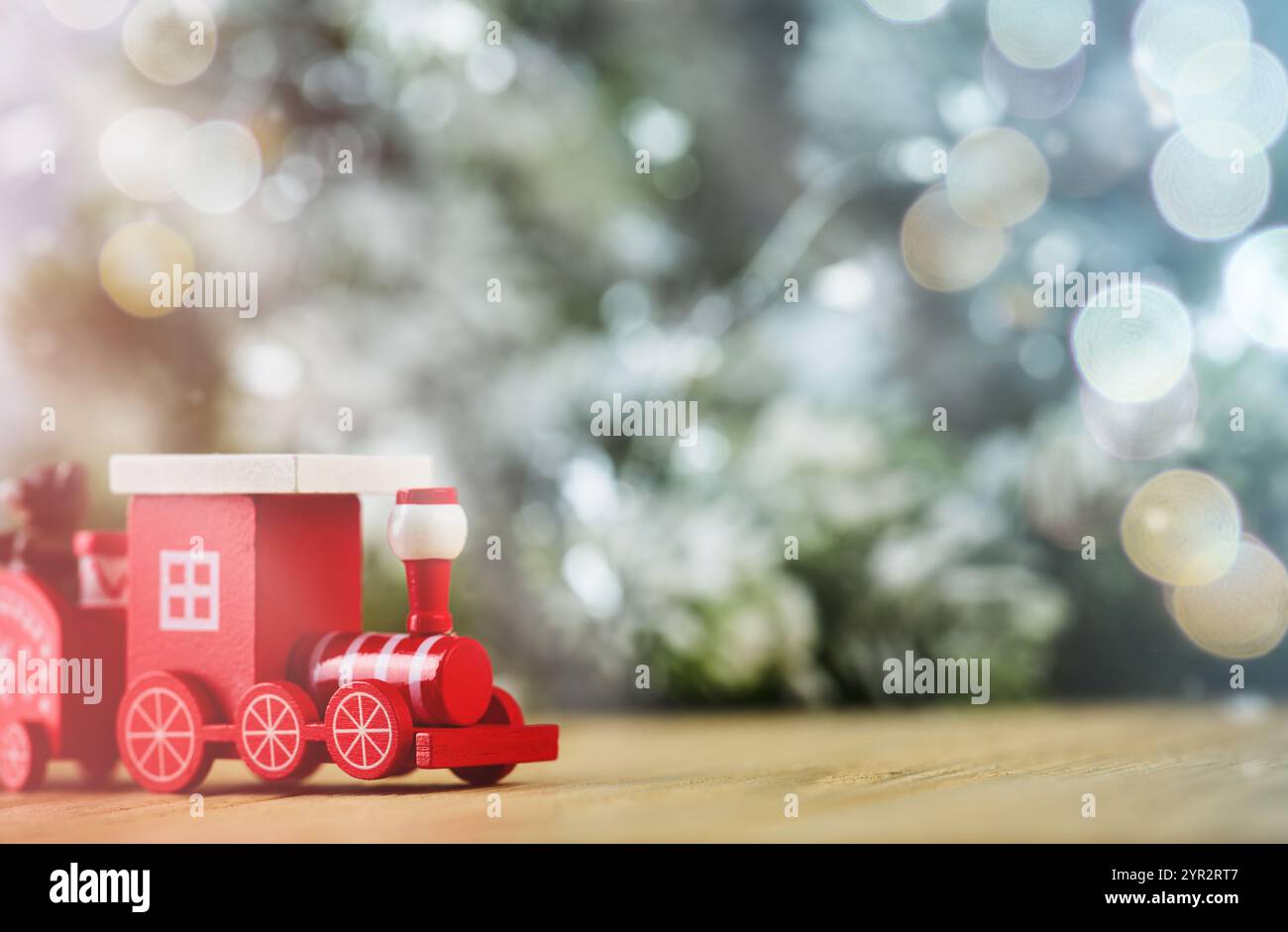 Giocattolo del treno di legno natalizio sullo sfondo di neve, bokeh e albero di Natale. Capodanno e Natale. Sfocatura morbida. Foto Stock