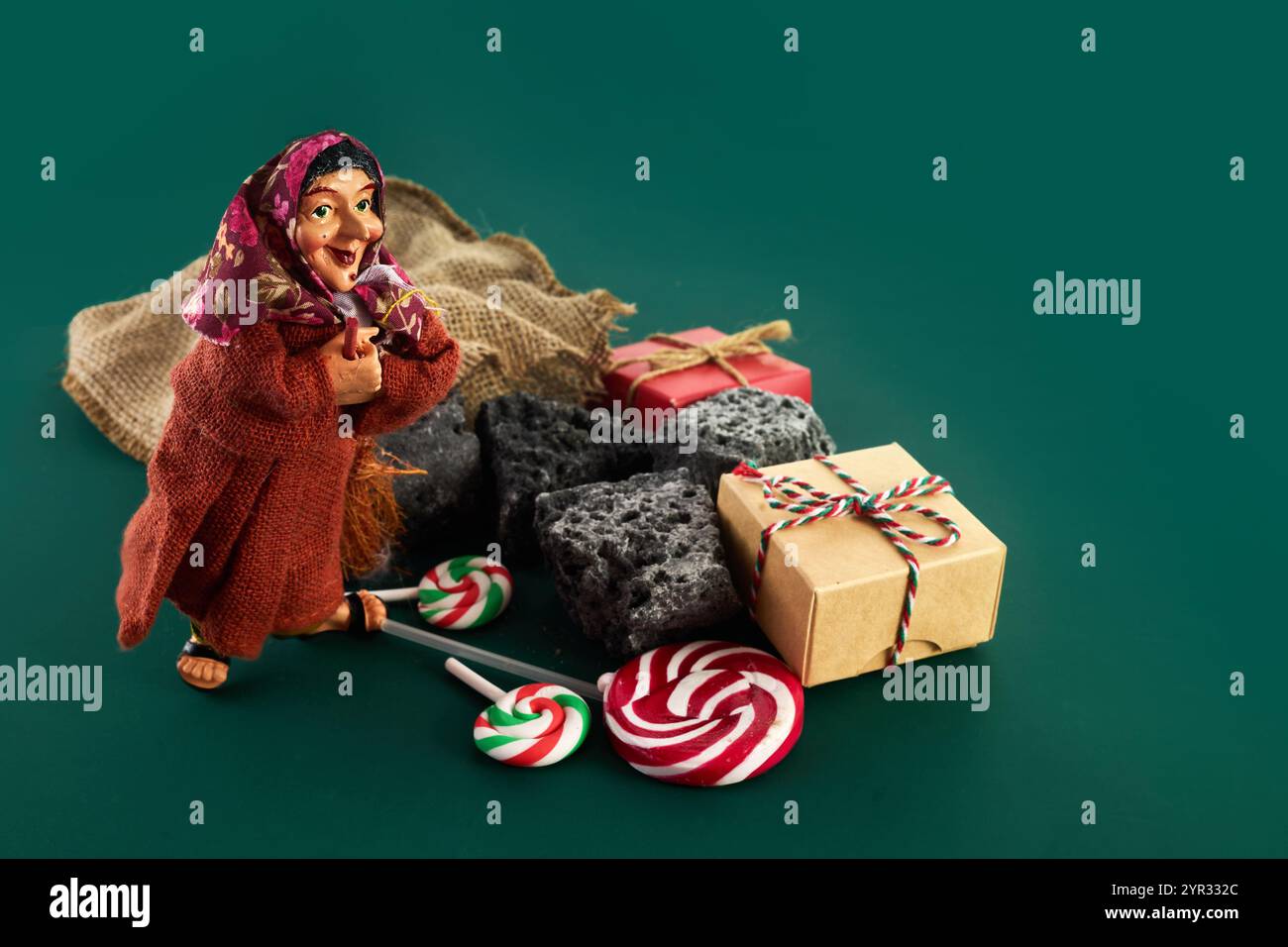 La Befana con carbone dolce e caramelle su sfondo verde. Tradizione italiana del giorno dell'Epifania Foto Stock