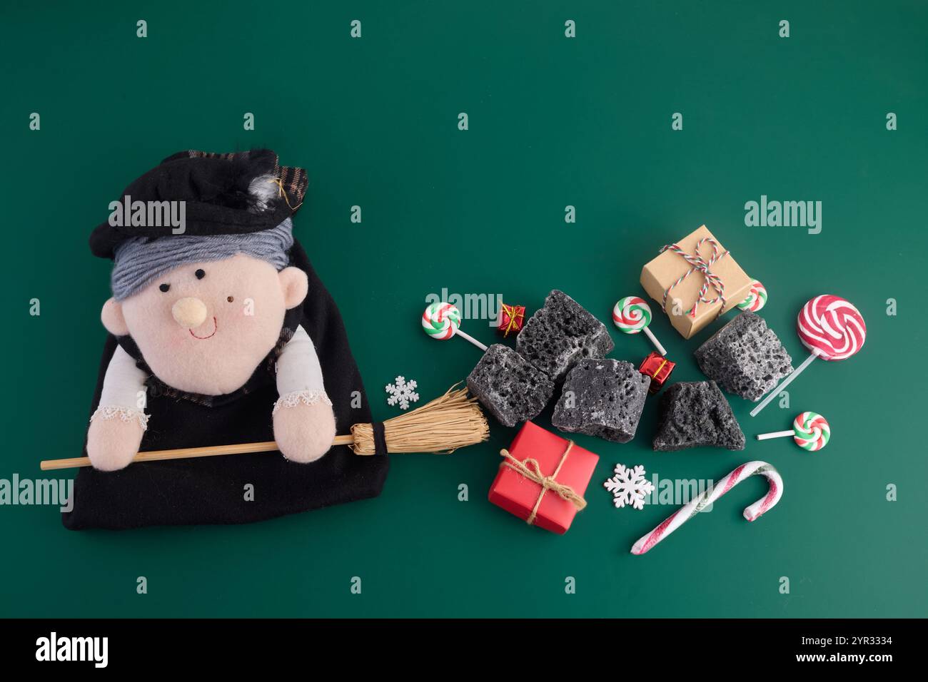 La Befana con carbone dolce e caramelle su sfondo verde. Tradizione italiana del giorno dell'Epifania Foto Stock
