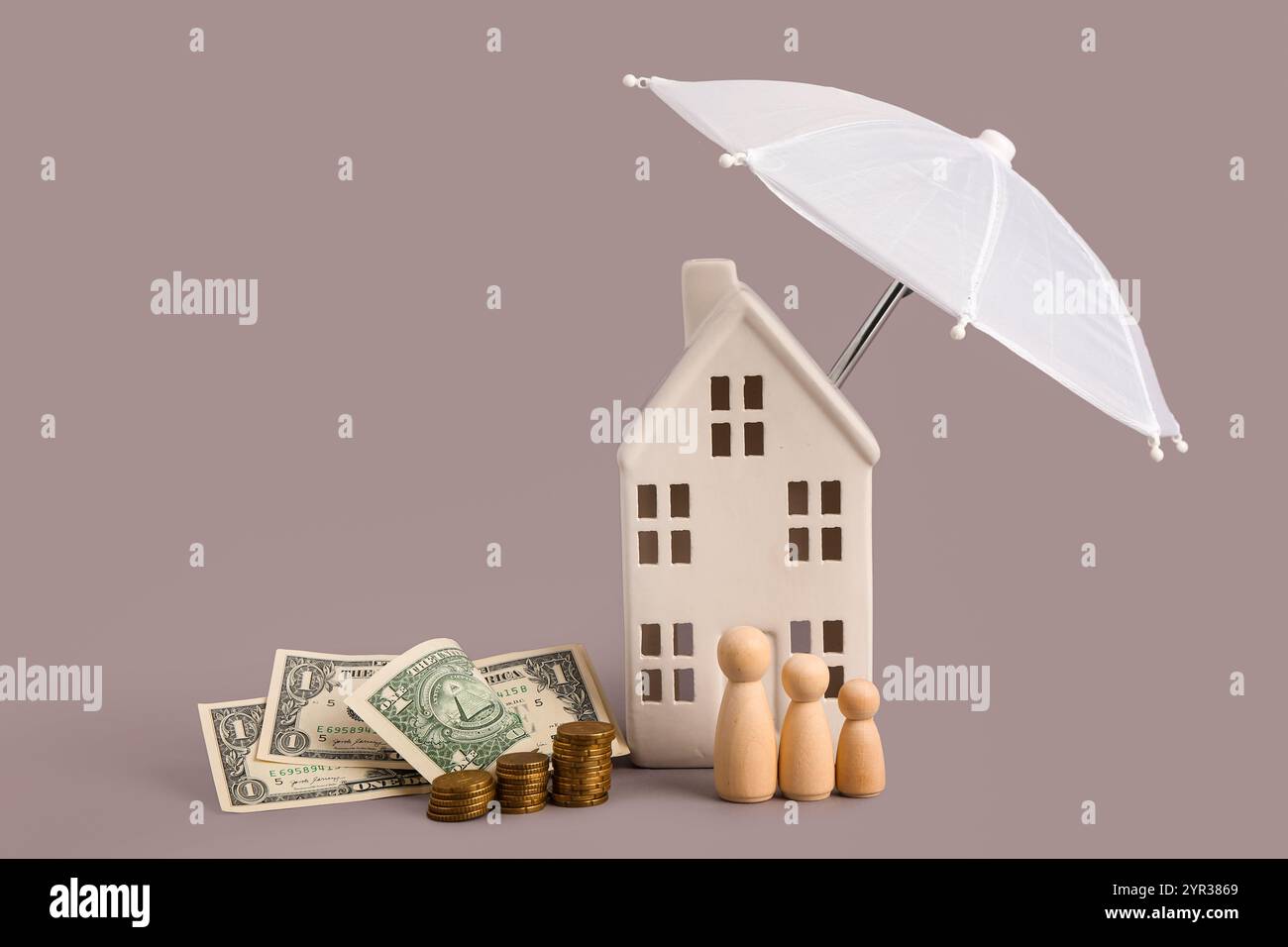 Composizione con casa decorativa, mini ombrello, denaro e figure in legno di famiglia su sfondo grigio Foto Stock
