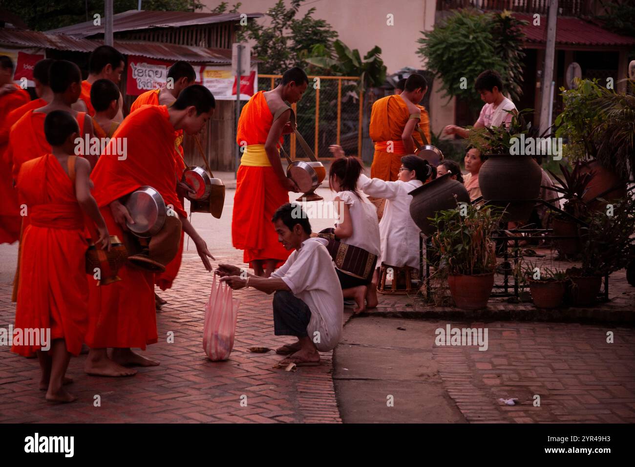 Luang Prabang, Laos - 9 aprile 2011: La processione mattutina dei monaci, a partire dalle 05:30: Monaci e novizi rivestiti di zafferano emergono sul Foto Stock
