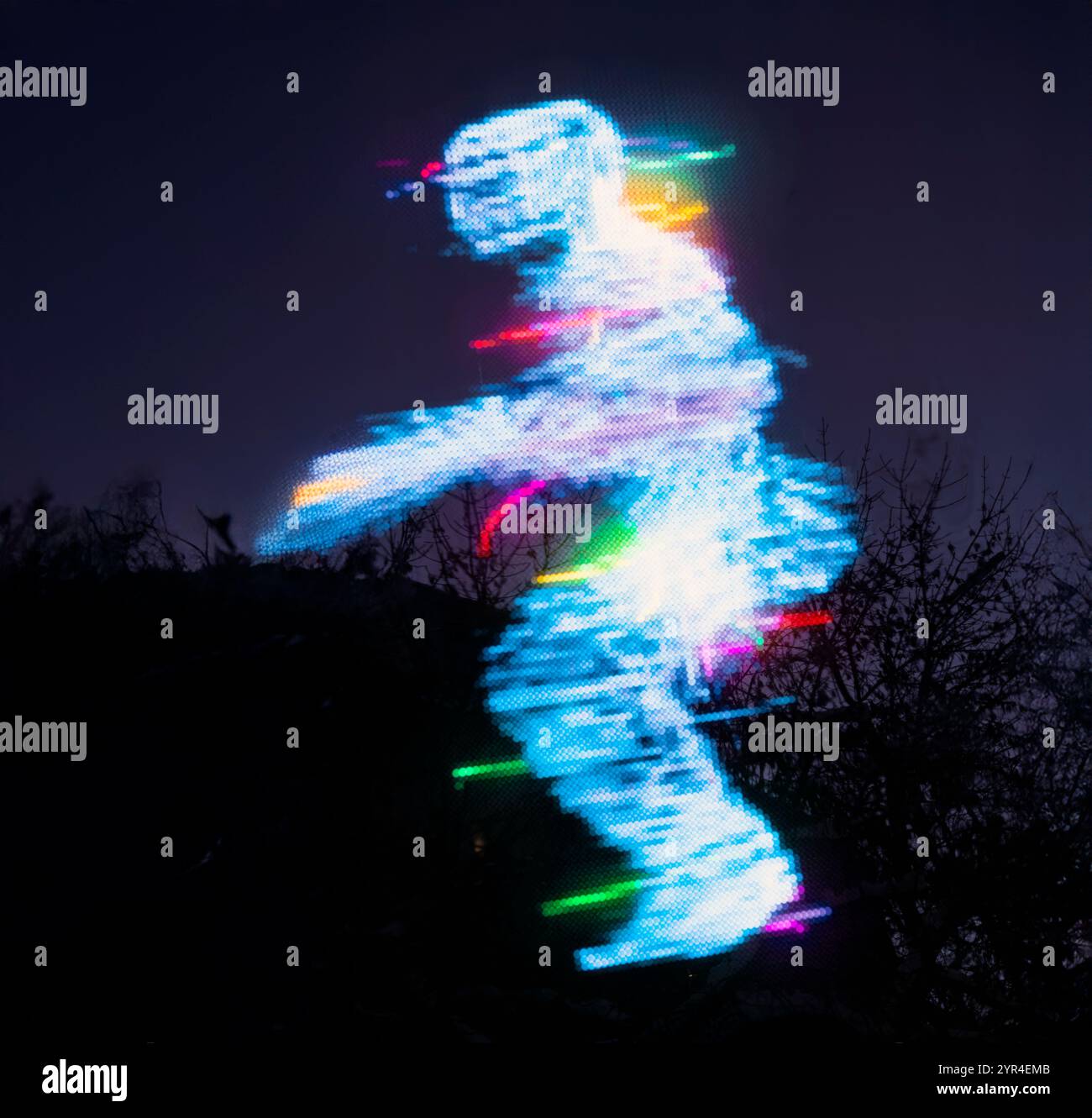 Una vivace fotografia a lunga esposizione che raffigura una figura fantasma umana creata da colorate tracce di luce su uno sfondo scuro all'aperto Foto Stock