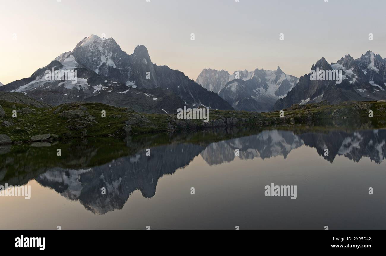 Crepuscolo sul lago di montagna Lacs des Cheserys nella riserva naturale Aiguilles Rouges, con Aiguille verte, Aiguille du Dru e Grandes Jorasses pisello Foto Stock