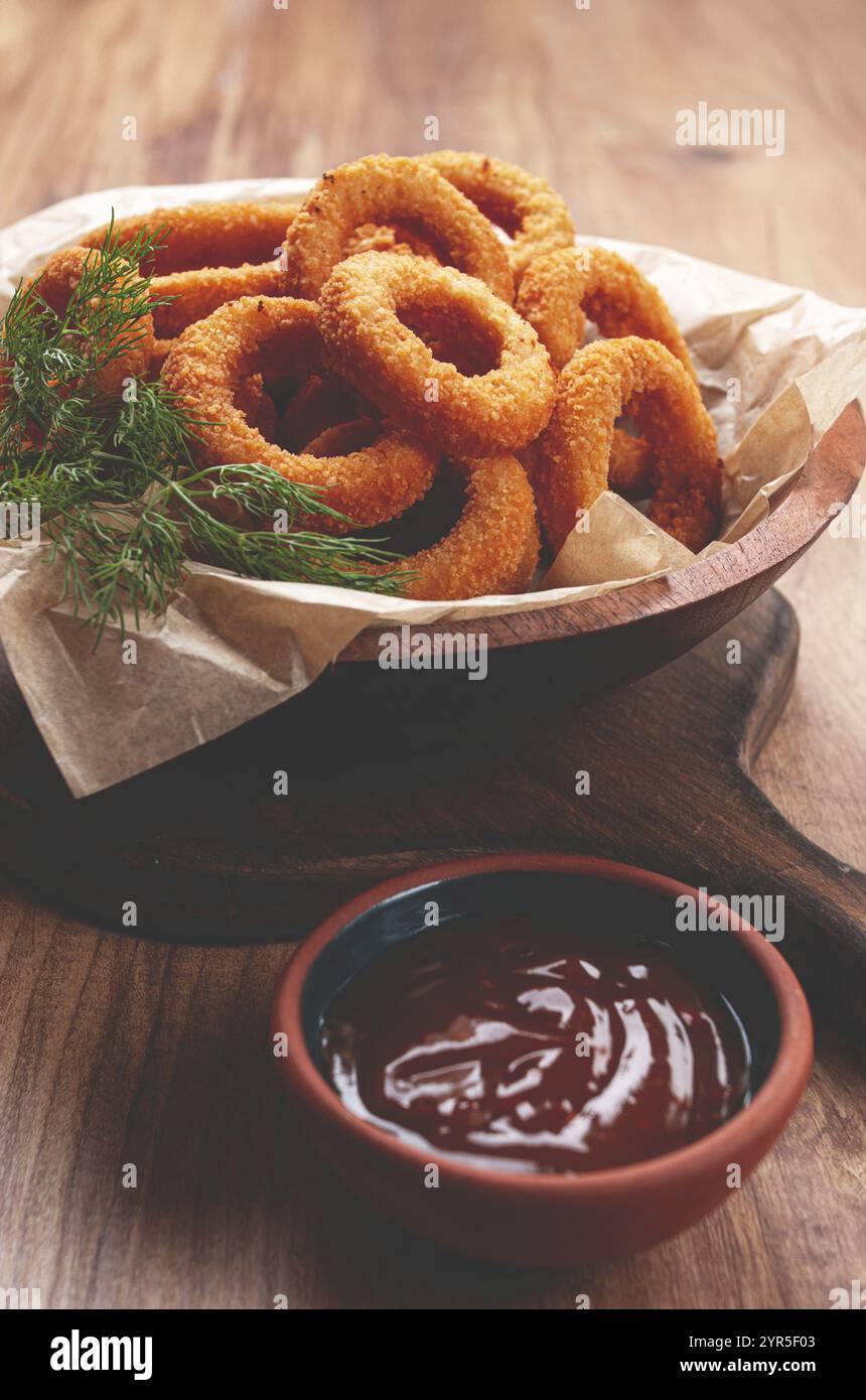 Anelli di cipolla fritti in profondità, antipasto, con salsa di pomodoro, su un tavolo di legno, nessun popolo, piatto preferito Foto Stock