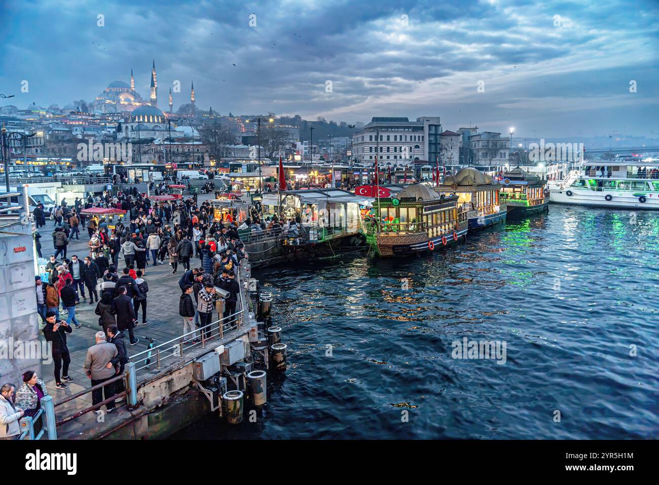 Istanbul - 9 gennaio 2022. Le Fish Sandwich Boats ormeggiate nel molo di Eminonu alla foce della Baia del Corno d'Oro e dello skyline del quartiere di Eminonu Foto Stock