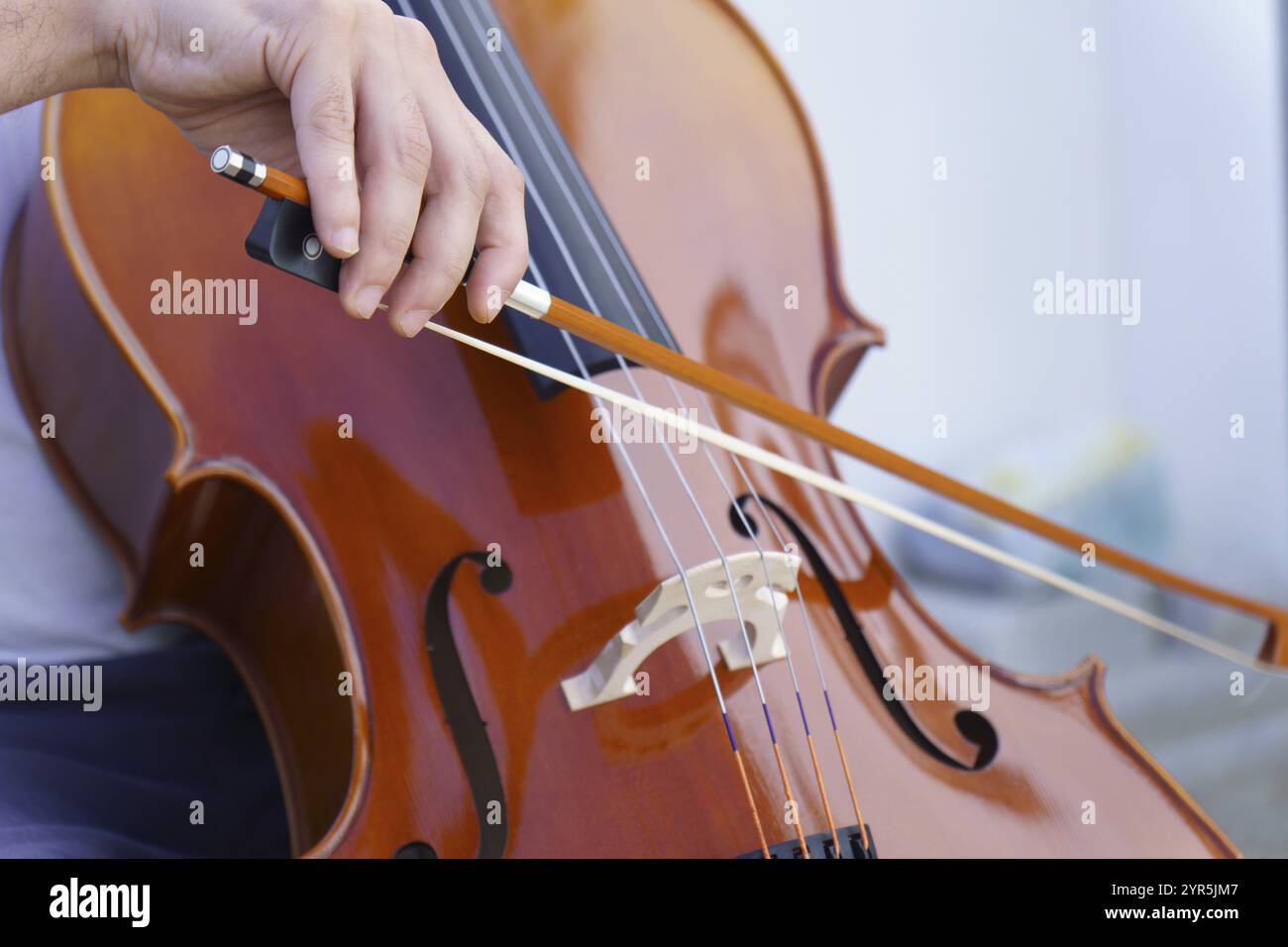 Mani di un uomo irriconoscibile che suona il violoncello su uno sfondo bianco e copia spazio Foto Stock