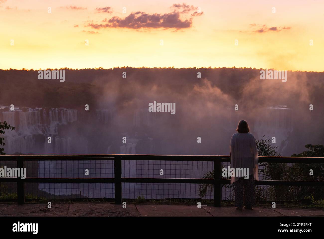 Tramonto delle cascate dell'Iguazú - una donna visitatrice turistica che guarda il tramonto dal lato brasiliano delle cascate dell'Iguazú; vacanza in Brasile, Sud America Foto Stock