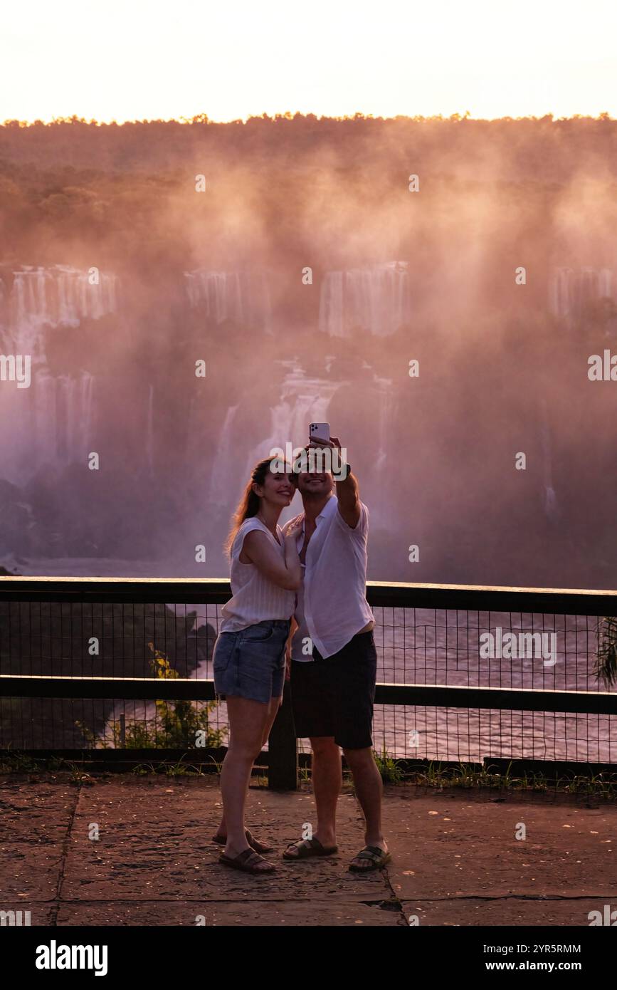 Cascate dell'Iguazú, romantica coppia turistica che scatta una foto selfie al tramonto; cascate dell'Iguazú lato Brasile, Brasile Sud America. Turismo e viaggi in Brasile. Foto Stock