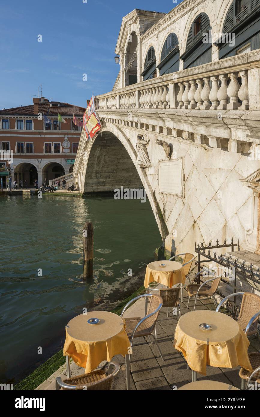 Bellissimo Ponte di Rialto in città e sul Canale d'acqua e ristorante tavolo e sedia in una giornata di sole con cielo azzurro a Venezia, Veneto, Italia, Europ Foto Stock