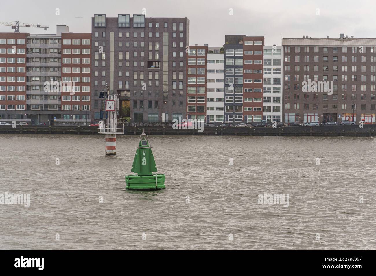 Vista sul fiume con boa verde in primo piano e moderni edifici residenziali sullo sfondo, Amsterdam, Paesi Bassi Foto Stock