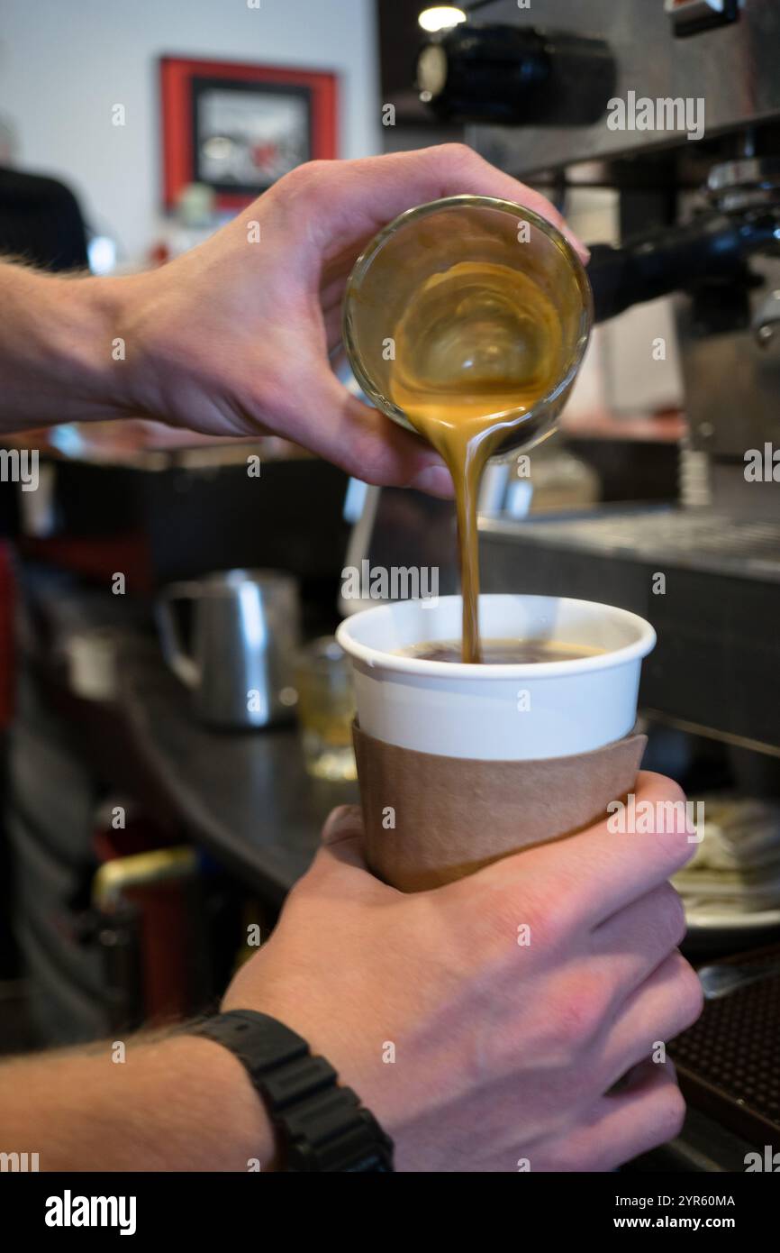 Il barista versa un espresso fresco in una tazza da caffè in un caffè Foto Stock