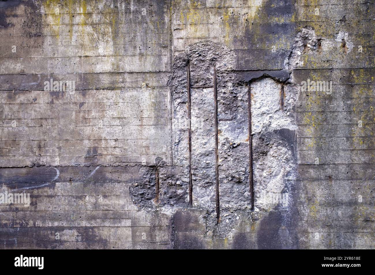 Una parete in cemento con grandi incrinature e aste metalliche esposte, che mostrano un notevole decadimento Foto Stock