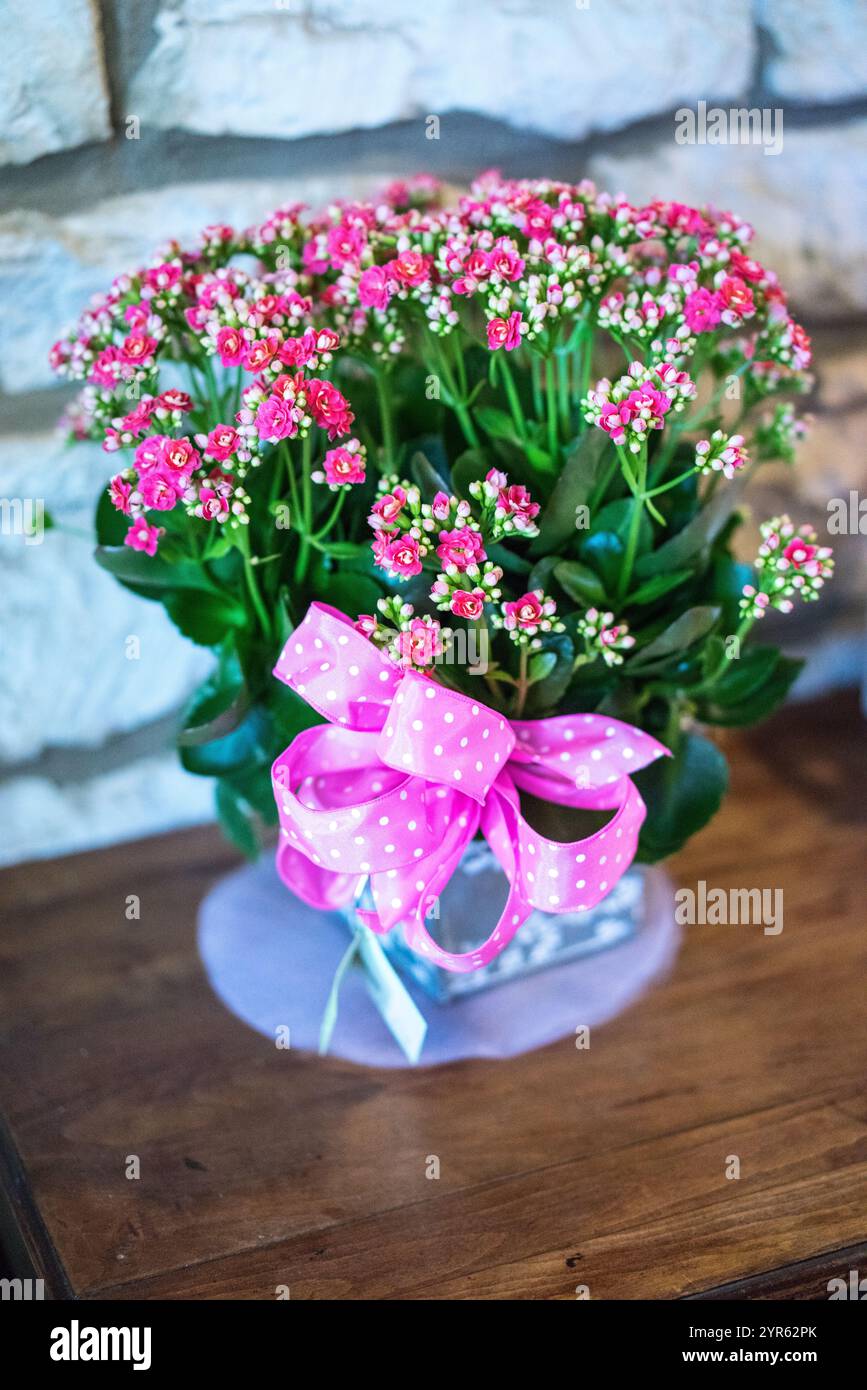 Affascinante allestimento di fiori rosa con nastro a puntini polka su tavolo in legno Foto Stock