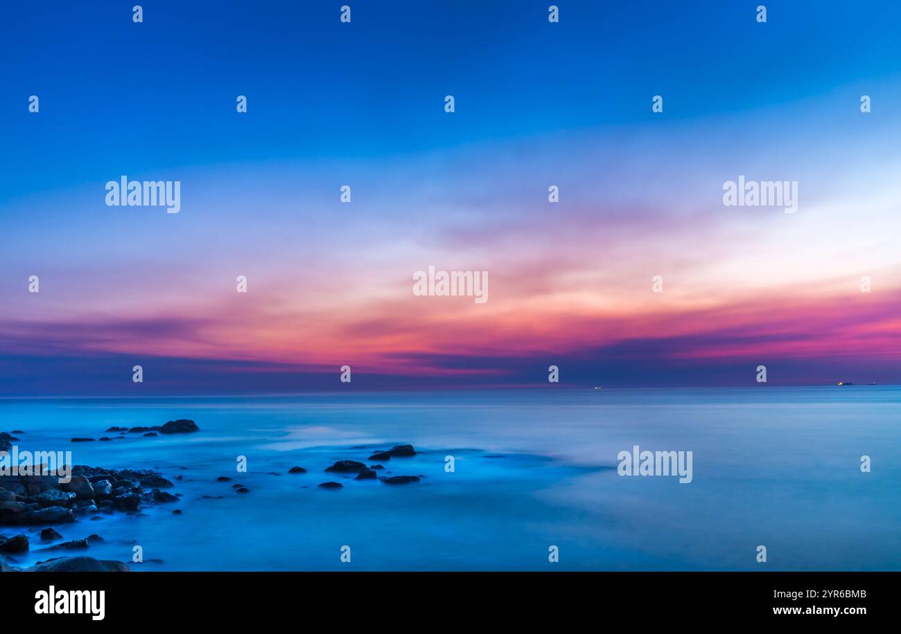 Colori pastello tenui dipingono il cielo sopra le calme acque dell'oceano atlantico durante un tramonto mozzafiato a vila nova de gaia, portogallo, Foto Stock