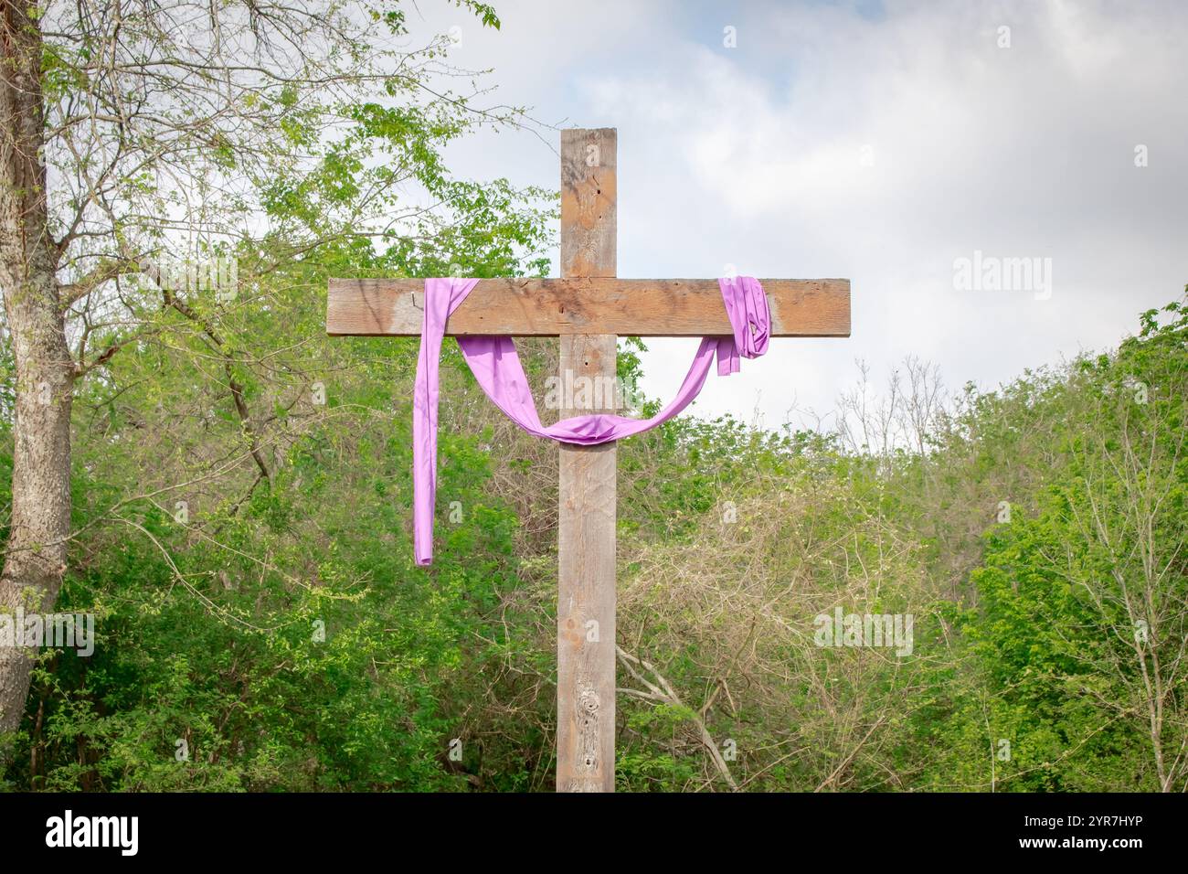 Croce in legno con un panno satinato viola. Lo sfondo è arbusto verde. Foto scattata alla missione San Juan a San Antonio in Texas Foto Stock