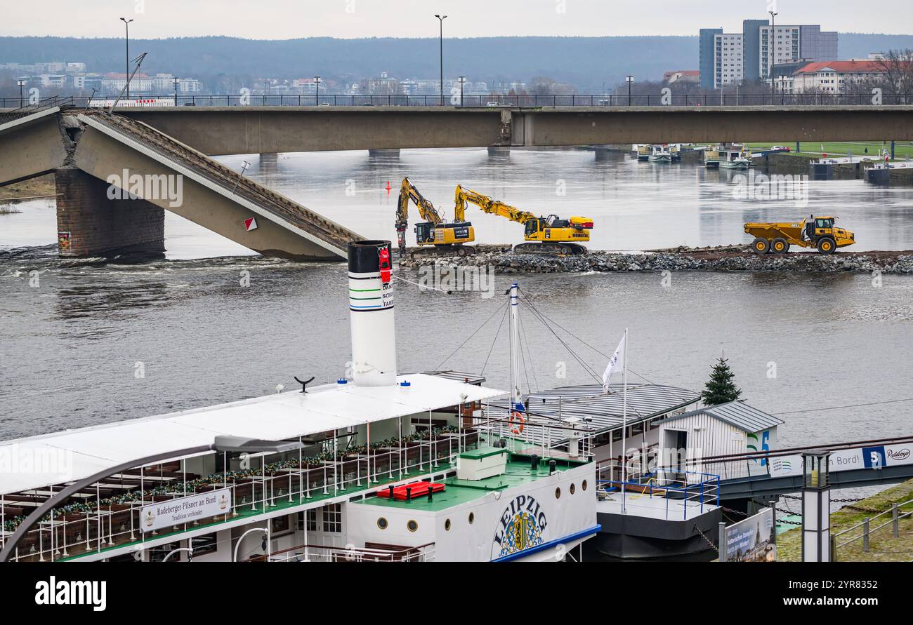 Dresda, Germania. 2 dicembre 2024. Gli escavatori sono impegnati a costruire una strada di costruzione e demolire il ponte crollato di Carolabrücke sul lato della città vecchia dell'Elba, con il piroscafo a pale "Lipsia" del Sächsische Dampfschifffahrt in primo piano. La sezione occidentale del ponte con i binari del tram, la pista ciclabile e il sentiero è crollata nella notte dell'11 settembre 2024 per ragioni sconosciute. Crediti: Robert Michael/dpa/Alamy Live News Foto Stock