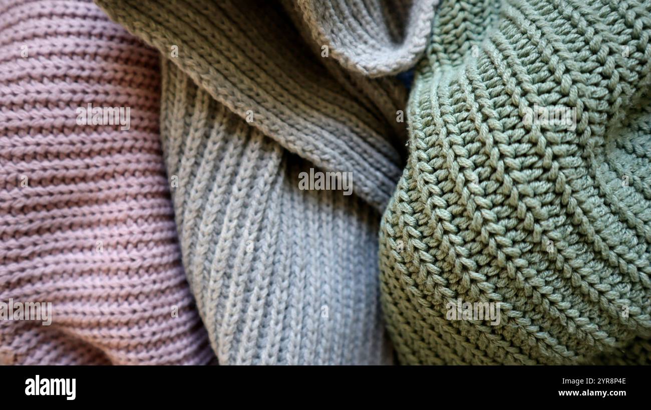 Lo sfondo è riempito di tessuto lavorato a maglia di colori grigio, turchese e viola. Tessuti di diversi colori sono disposti in modo casuale. Il tessuto è piegato. Differ Foto Stock